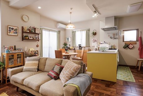 ドラマ『時すでにおスシ!?』に採用されたフラットオープン型の黄色いキッチン。ダイニングのソファ越しのキッチン。